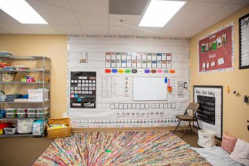 Brighten Academy Preschool classroom with brightly colored rug and educational materials on the walls