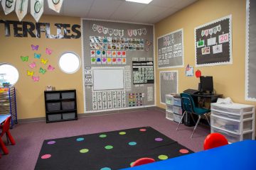 Carpet time area of a Brighten Academy Preschool classroom with rainbow dotted carpet on floor